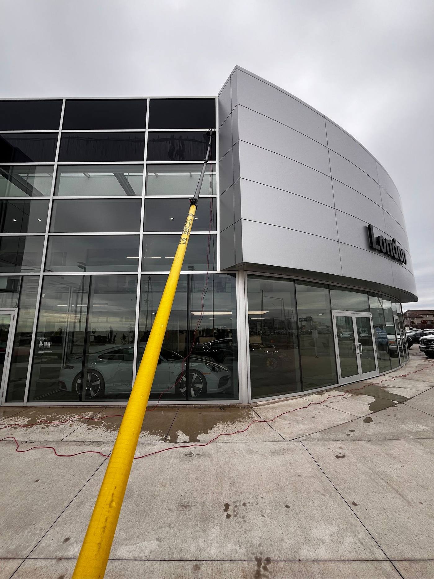 Water-fed pole reaching the upper glass on a car dealership