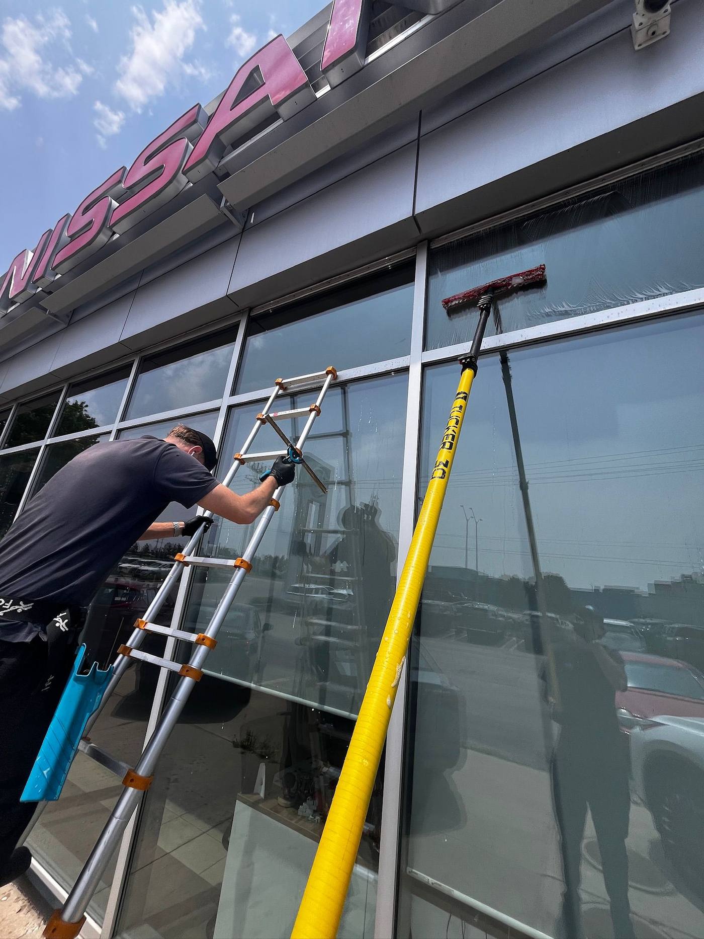 Ladder work across a car dealership storefront