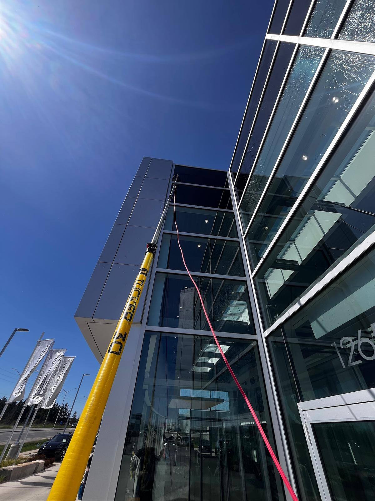 Water-fed pole on the angled glass of a modern building